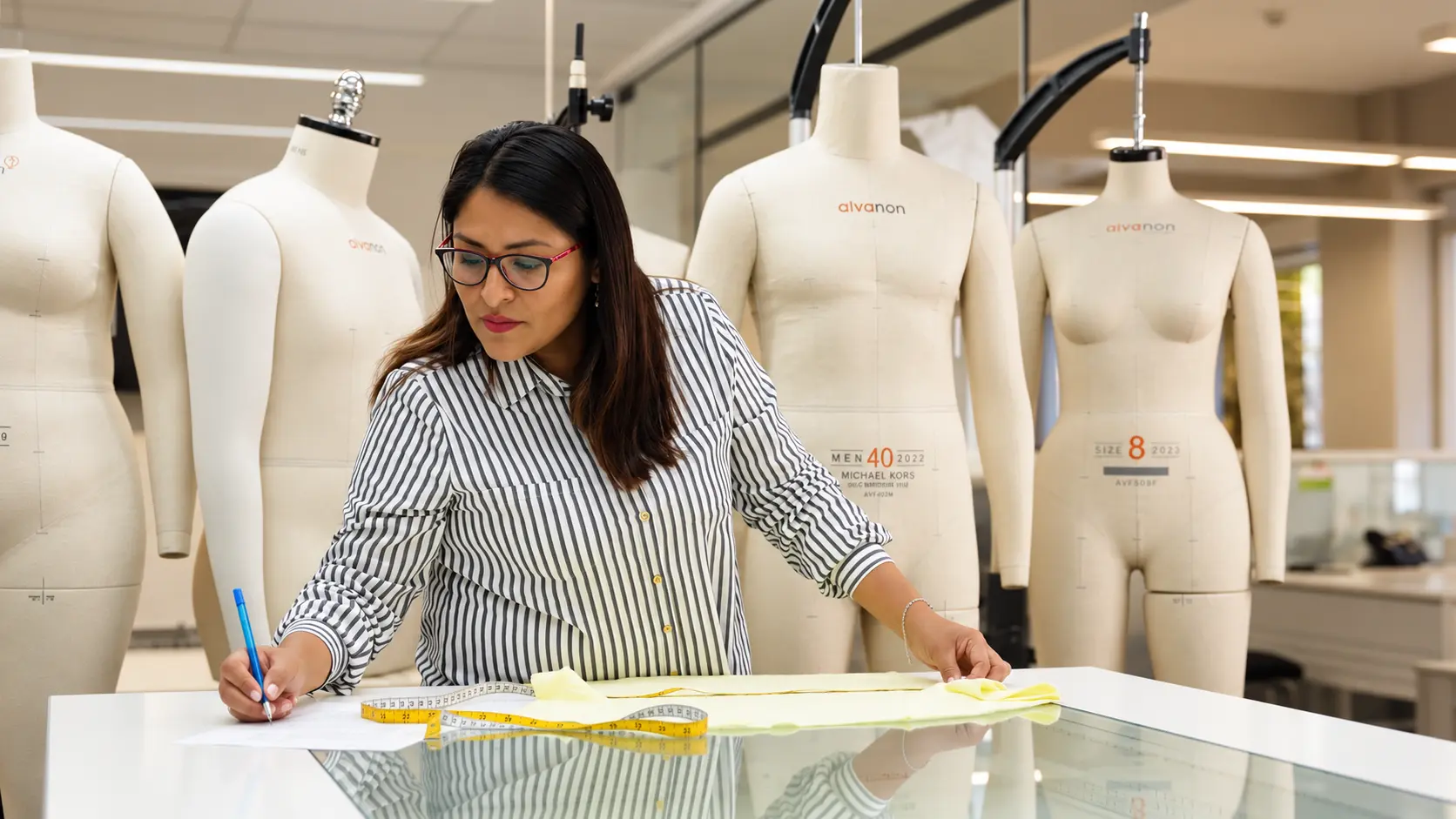 WTS patternmaker working with measurement tape and mannequins